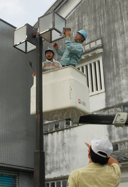 高所作業車で街路灯を掃除する電気工事組合員