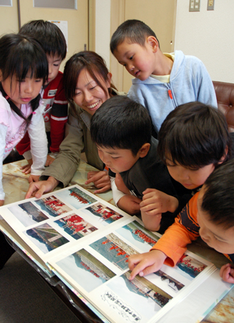 １５年前の開園式を教え子たちにアルバムで見せる起塚裕子教諭