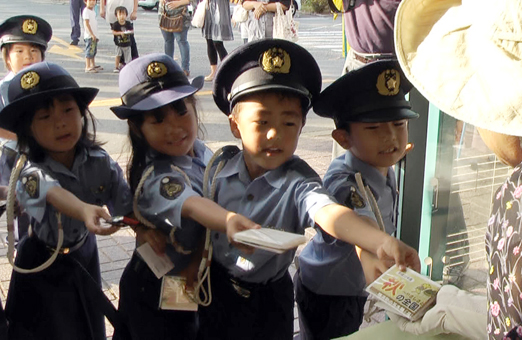 “ちびっこ警察官”に扮して交通安全グッズを配る城西幼稚園児