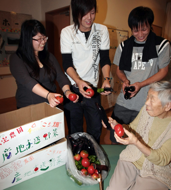 農業体験で収穫した夏野菜をお年寄りに手渡す赤穂高定時制の生徒たち