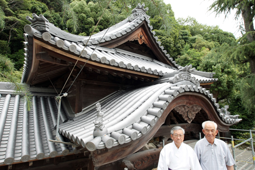 瓦を９２年ぶりに全面的に葺き替えた荒神社の社殿。大嶋宮司(左)と綿田総代会長