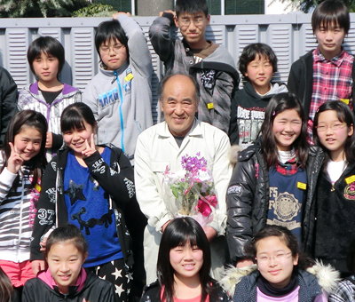 感謝の品を贈った卒業生たちと記念写真に収まる船津吉敬さん＝保護者提供