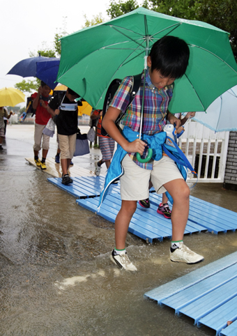 学校から早退する児童たち。校門には大雨で水たまりができていた＝９月４日午前１０時１２分撮影