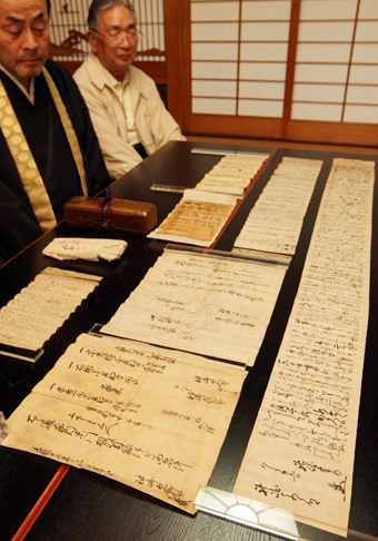 明顕寺所蔵の義士関連史料と内藤雅文住職(左)、米田末雄総代