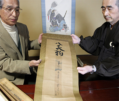 赤穂義士・大高源五の自筆短冊を表装した掛け軸を寄贈した米澤晴實さん(左)