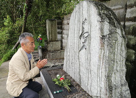 「夢」と彫字された顕彰碑に手を合わせる辰巳柳太郎の長男・新倉寿夫さん。顕彰碑は辰巳が愛した坂越の海を臨む高台にある