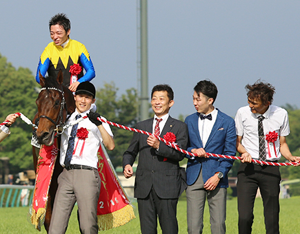 関係者らとともにダービー制覇の記念写真撮影に応じる友道康夫調教師=中央=