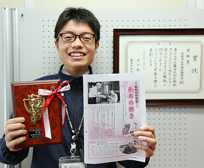 近畿市町村広報紙コンクールで奨励賞を受賞した「あこう社協だより」と編集担当の荒尾慎平さん