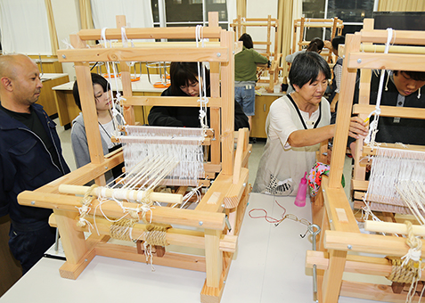 ＯＢの茶谷誠さん＝左端＝がつくった小型織機で行われている赤穂緞通製作体験
