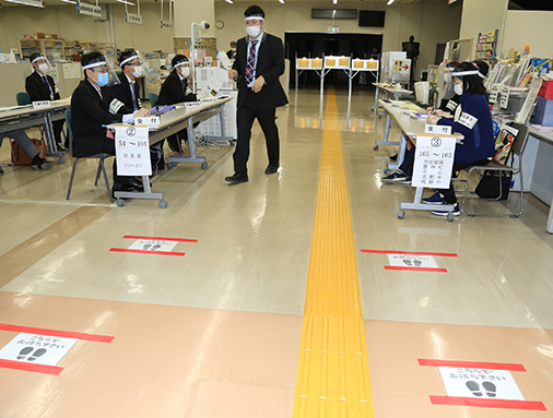 間隔を空けて列に並ぶように促すサインが床に貼られた投票所