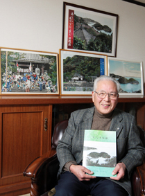 発刊した切り絵集を手に坂越への思い入れを語る佐方直陽さん。後ろにあるのが作品例