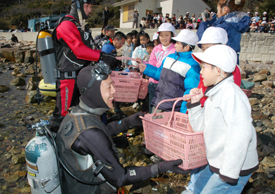 児童が育てたアマモ苗を受け取るダイバー