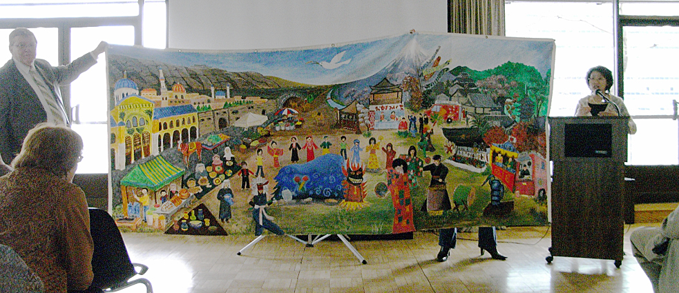 子どもたちの描いた絵を見せながら活動を紹介する塩飽さん