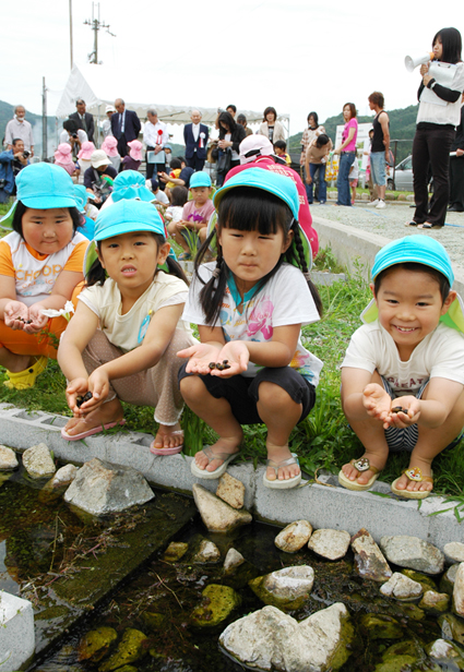 カワニナをビオトープに放す子どもたち