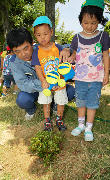 植樹したサツキツツジに水をやる園児