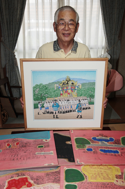 入選作を手に笑顔の竹田忍さん。手前にあるのは版木