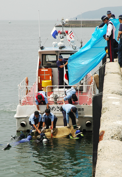 海底で見つかった男性の遺体を引き揚げる捜査員