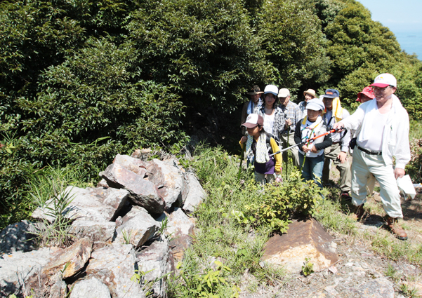 石塁の前で上杉太郎さん=右端=の解説を聞く参加者