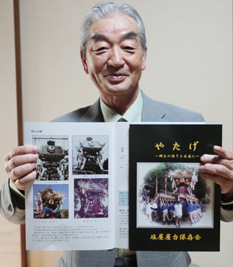 冊子「やたげ〜郷土の誇りを永遠に〜」を手にする塩屋屋台保存会の山田春美会長