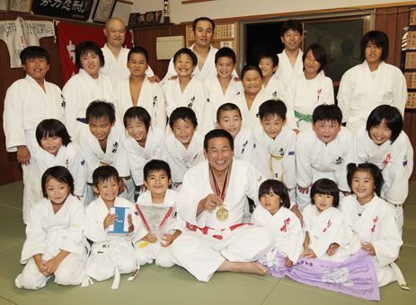 ２度目の金メダルを胸に教え子らに囲まれ笑顔の池田正男さん＝前列中央