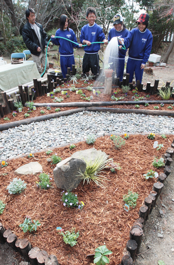 完成した花壇に水やりする生徒たち