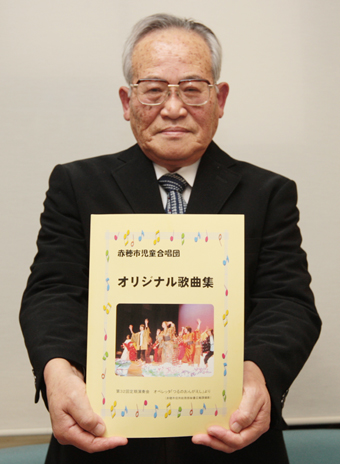 発刊した「オリジナル歌曲集」を手にする西原賢団長