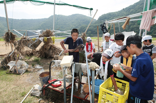 泥に汚れた用具を水洗いする団員たち