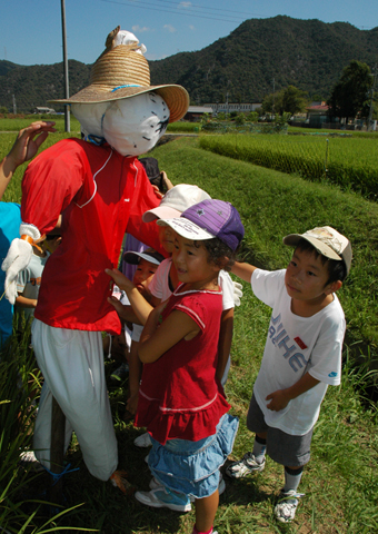 手作りしたかかしを田んぼに立てた高雄小の子どもたち