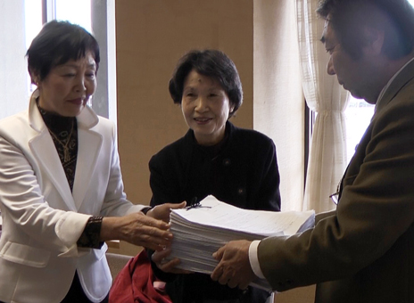 ごみ処理有料化の撤回を求めて請願書と署名簿を渡す上杉泰子代表=中央=と三志多文代代表=左=