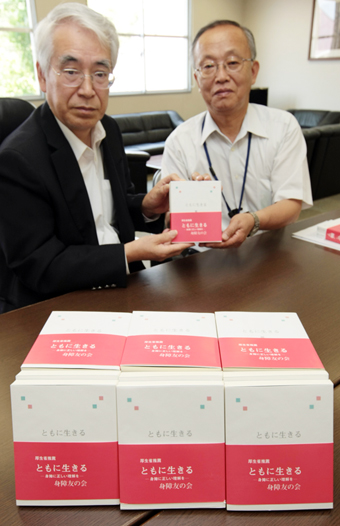 書籍「ともに生きる」を寄贈する柏朋会代表幹事の安井秀作さん(左)