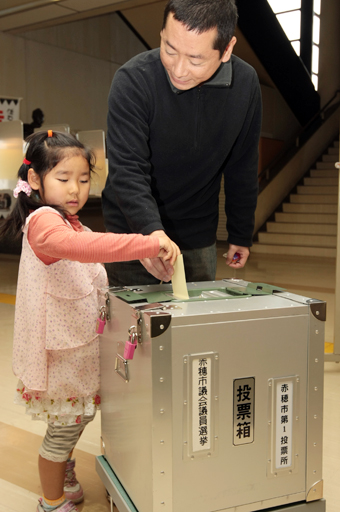 子どもと一緒に一票を投じる有権者