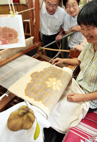 「ひょんの実」=手前=を染料に使った赤穂緞通に取り組む=右から=根来節子さん、小田中久良子さん、田川芳弘さん。