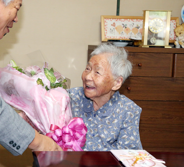 お祝いの花束を受け取って笑顔をみせる赤穂市内女性最高齢者の原田そのさん
