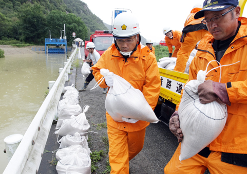 周世の黒谷川沿いに土のうを積む市職員。写真左奥が樋門