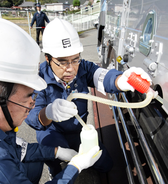 車両の燃料タンクから調査のための軽油を採取する県税事務所職員