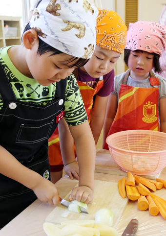 小1児童と園児たちが野菜を切った交流カレー作り