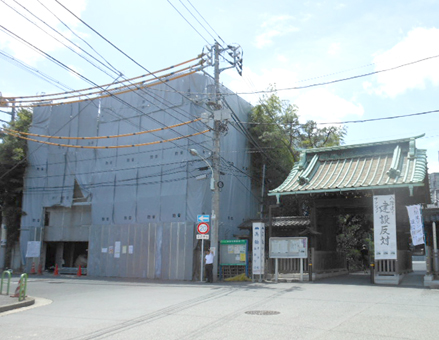 「八階建てマンション建設反対」の看板とのぼりが立つ泉岳寺の中門。門の左側のシートで覆われた場所が建設予定地
