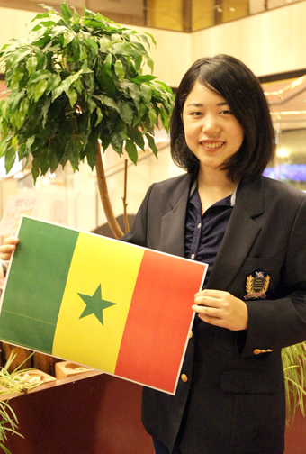 「現地の人たちとの交流を大切にしたい」と赴任先のセネガル国旗を手にする前田智帆さん