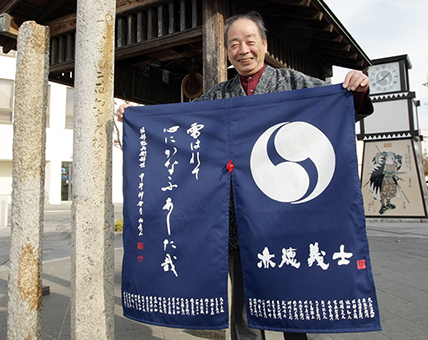 堀部弥兵衛の句をあしらった創作のれん。左の石柱が句碑