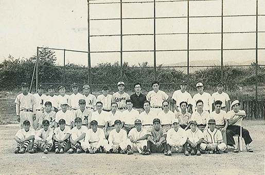 昭和28年夏にOBを交えて開かれた紅白戦の集合写真。奥に寄贈の鉄骨で出来たバックネットが見える=木村國勇さん提供