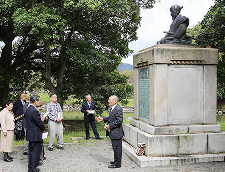 山鹿素行像前で台座の碑文解説を聞く人たち