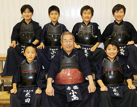 指導している子どもたちに囲まれて笑顔の小島勝義さん