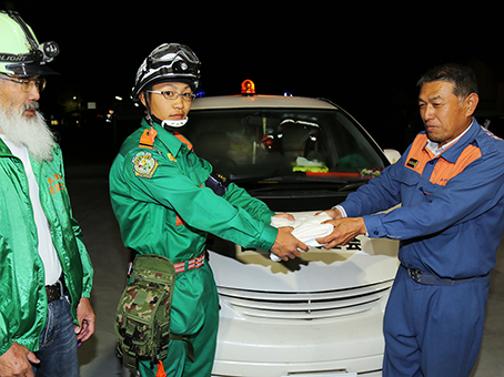 山尾さんと八瀬さんに物資を渡した河部さん(右)