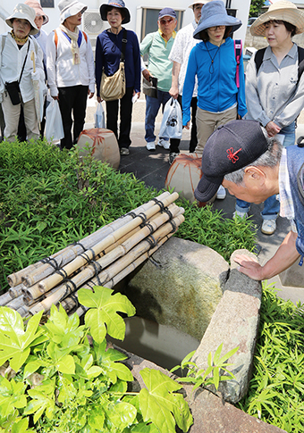 各戸給水のなごりを示す汲出桝跡をのぞき込む参加者
