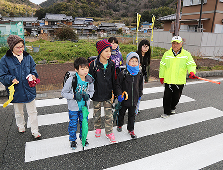 吉栖清美さん(右)や大人に見守られ、国道交差点を渡る子どもたち