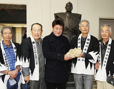 「手作り文化伝承の会」からわらじを贈られた柴田善明さん＝中央。今回で４１年連続の義士祭見物となった
