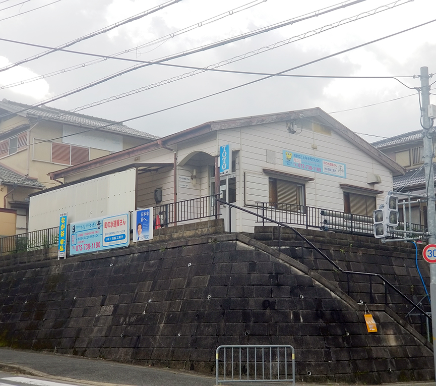 大阪府豊能町にある東洋開発工業所。建物壁面とフェンスには「町の水道屋さん」と書かれた看板があり、別会社との共用とみられる
