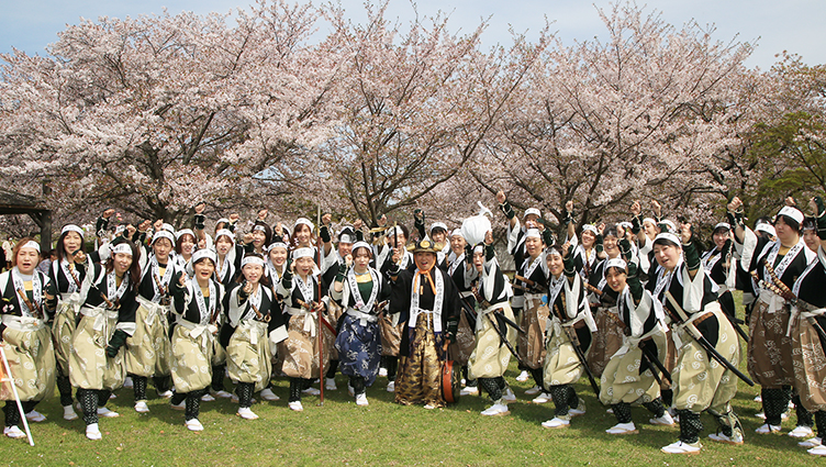 桜を背に勝ちどきをあげる女人義士行列の一行